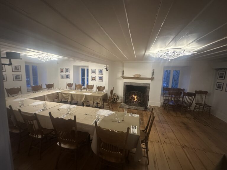 Tables set in the dining room at Auberge du Manoir with a lit fireplace.