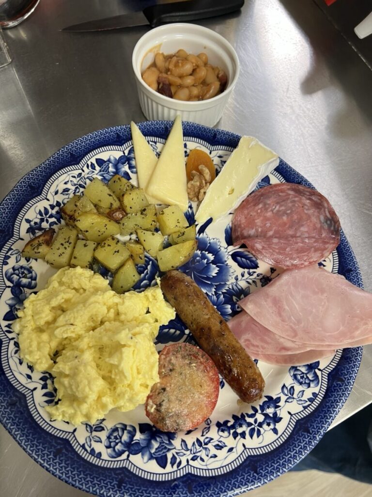 Breakfast plate with eggs, potatoes, cold cuts and side dishes.